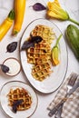 Savory zucchini waffles with herbs served with sour cream sauce. Top view.