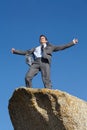 Savouring a moment at the top. A young businessman standing with his arms raised in victory atop a cliff. Royalty Free Stock Photo