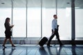 Savvy business travelers. businesspeople walking down a corridor in an airport while on a business trip. Royalty Free Stock Photo