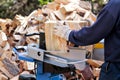 Saw cutting wood for winter. A man cutting firewood for the winter using a modern machine lumber saw. Royalty Free Stock Photo