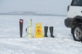 Saw, ice drill auger, signboard and boots on a snow