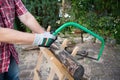 Sawing firewood manually with a hacksaw on a wooden sawhorse