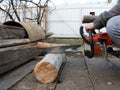 Sawing a log with a chainsaw in a peasant yard Royalty Free Stock Photo