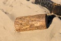 Sawn wood log in the sand on a beach next to burnt remains of campfire Royalty Free Stock Photo