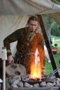 A Saxon using bellows to stoke up a fire at the reenactment of The Battle of Hastings in the UK