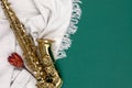 Saxophone on a green background with a blanket and a flower, top view.