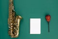 Saxophone on a green background and notepad, top view.