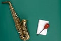 Saxophone on a green background and notepad, top view.