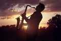 Saxophonist playing sax against sunset