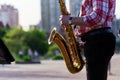 Saxophonist plays a golden saxophone on the street with passers-by in sight. spring. musical reed wind instrument. tongue wooden