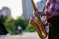 Saxophonist plays a golden saxophone on the street with passers-by in sight. spring. musical reed wind instrument