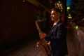 Saxophonist plays the sax on darke street at night