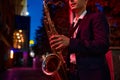 Saxophonist plays the sax on darke street at night