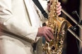 The saxophonist in a white suit plays solo on a saxophone. Close-up.