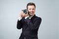 Say cheese concept. Handsome young man in suit holding in arms small camera ready to make a shoot. Royalty Free Stock Photo