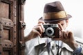 Say cheese. Detective capturing a photo from around the corner while using a retro camera. Royalty Free Stock Photo