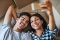 Say cheese. a happy young couple taking a selfie while lying on the floor of their new home. Royalty Free Stock Photo