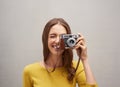 Say cheese. Studio portrait of an attractive young female photographer posing with her camera against a grey background.