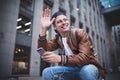 Say hello. Happy man meeting someone. Happy man listening to music with headphones from a smartphone on the street. Royalty Free Stock Photo