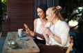 Say hi to my friend. two young women looking at something on a cellphone while sitting at a cafe. Royalty Free Stock Photo