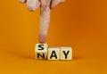 Say nay symbol. Businessman turns a cube, changes the word `say` to `nay`. Beautiful orange background. Copy space. Business,