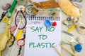 Say No to Plastic handwritten on notebook surrounded by real plastic pollution and natural beach shells Royalty Free Stock Photo