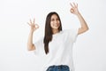 Say okay. Portrait of friendly-looking happy woman in white t-shirt and jeans, raising hands with great or acception