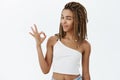 Say okay. Portrait of joyful calm and chill attractive dark-skinned woman with dreads winking and smiling showing ok or