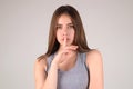 Say secret hush be quiet with finger on lips. Shhh gesture isolated on studio background portrait. Girl showing hush Royalty Free Stock Photo