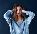 Say what. Studio portrait of a cute teenage girl looking surprised with her hands over her ears posing against a dark Royalty Free Stock Photo