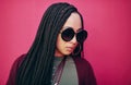 Say who you are with your style. a young woman with braids posing against a pink background.