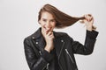 Saying goodbye to split ends. Studio shot of pleased happy young woman pulling hair with hand, smiling broadly and