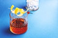 Sazerac, alcoholic cocktail drink with cognac, bourbon, absinthe, bitters, sugar and lemon zest. Dazzling blue background with