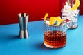 Sazerac, classic alcoholic cocktail with cognac, bourbon, absinthe, bitters, sugar and lemon zest. Dazzling red blue background
