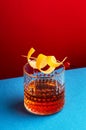 Sazerac, classic alcoholic cocktail with cognac, bourbon, absinthe, bitters, sugar and lemon zest. Dazzling red blue background