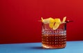 Sazerac, classic alcoholic cocktail with cognac, bourbon, absinthe, bitters, sugar and lemon zest. Dazzling red blue background