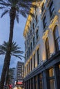 The Sazerac House on Canal Street with liquor stores, hotels, retail shops, lush green palm trees and people walking on the street