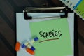 Scabies write on sticky notes isolated on Wooden Table. Medical or Healthcare concept