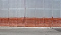 Scaffold plastic sheeting covering a facade under refurbishment, a sidewalk and an asphalt road.