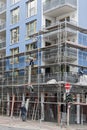 Scaffolding builders assemble a scaffolding in front of a blue house