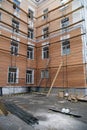 Scaffolding and fencing signal tape next to the outer wall of a multi-storey building. Repair and restoration of city houses