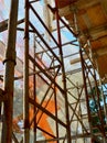Scaffolding in front of the repaired building is shrouded with construction safety net, view from inside, sunny autumn day Royalty Free Stock Photo