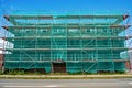 Scaffolding with green safety netting near a multi-story brick house under construction in Germany