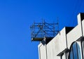 Scaffolding and lifting pulley at the top of a building in a construction area against blue sky