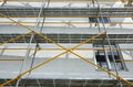 Scaffolding near a house under construction for external plaster works, high apartment building in city, white wall and window, ye Royalty Free Stock Photo