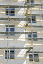 Scaffolding near a house under construction for external plaster works, high apartment building in city, white wall and window, ye Royalty Free Stock Photo