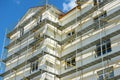 Scaffolding near a house under construction for external plaster works, high apartment building in city, white wall and window, ye Royalty Free Stock Photo
