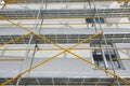 Scaffolding near a new house, building exterior, construction and repair industry, white wall and window, yellow pipe