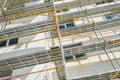 Scaffolding near a new house, building exterior, construction and repair industry, white wall and window, yellow pipe Royalty Free Stock Photo