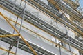 Scaffolding near a new house, building exterior, construction and repair industry, white wall and window, yellow pipe Royalty Free Stock Photo